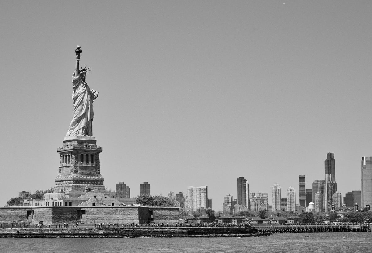 Black-and-white photo of the Statue of Liberty with a city skyline across the water